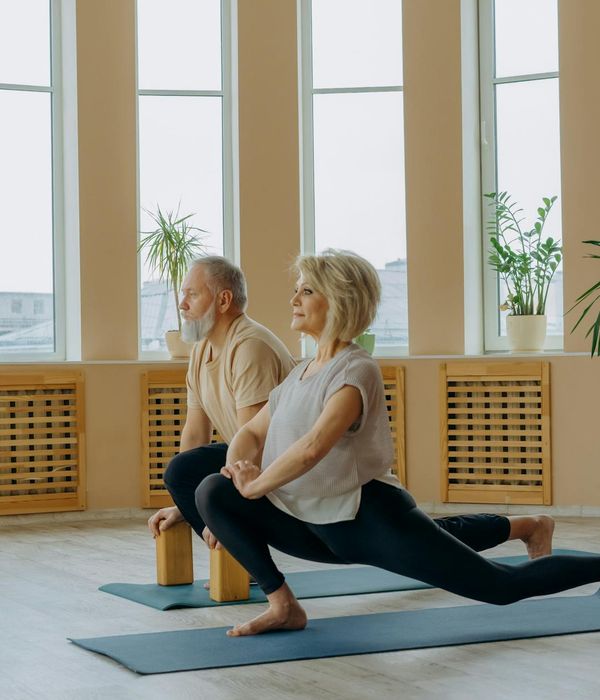 Woman performing a gentle yoga stretch in an olive-colored environment.